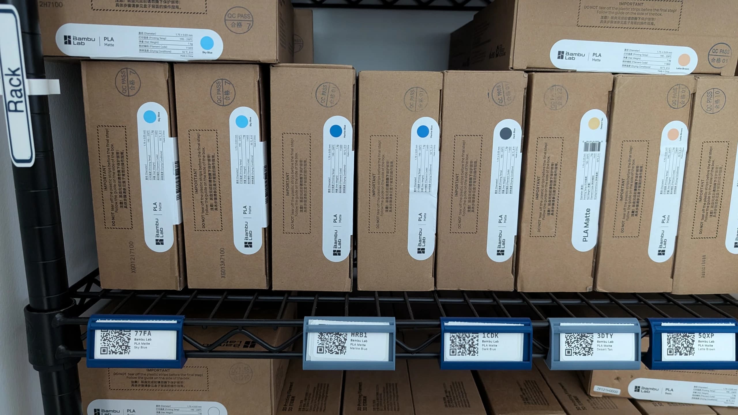 Shelf of QR-labelled filament boxes — every label matches a spool in the system